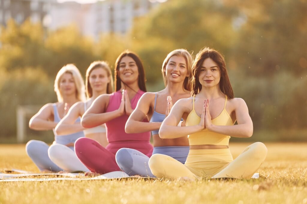 Calm meditation in lotus pose. Group of women have fitness outdoors on the field together