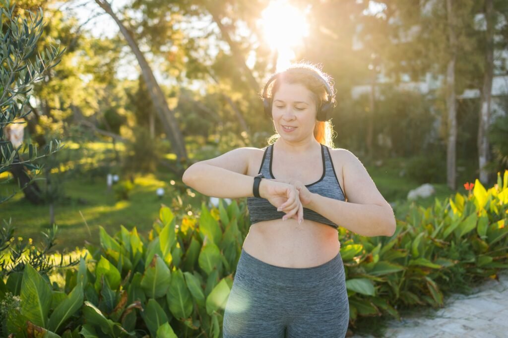 Fat woman checking time or heart rate from smart watch. Exercise or running outdoors for weight loss