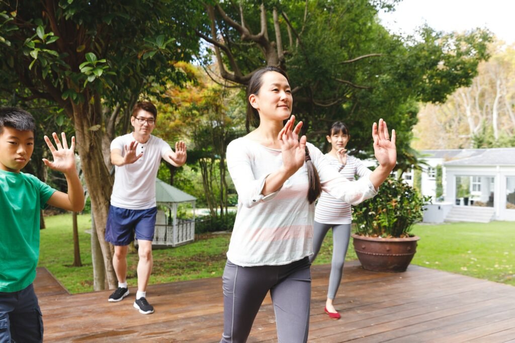 Happy asian parents, son and daughter exercising outdoors, practicing tai chi, Traditional Italian Healing