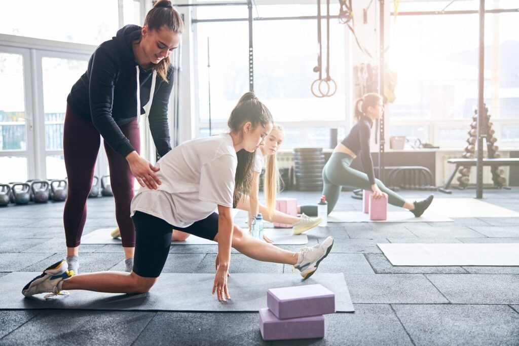 Professional gym coach guiding women with stretching