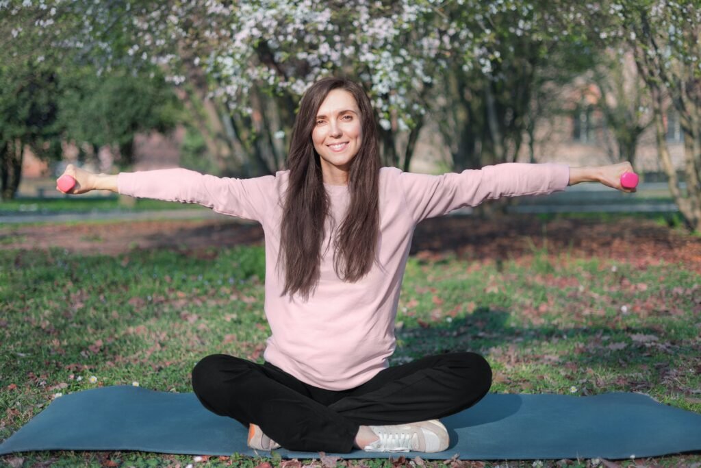 Young woman doing exercising on mat in the city park. Breathing practices and mental health.