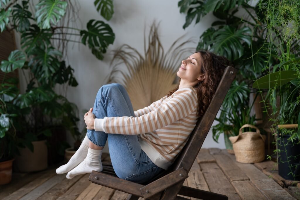 Happy calm peaceful woman dreaming with closed eyes and smile on face in tropical greenhouse