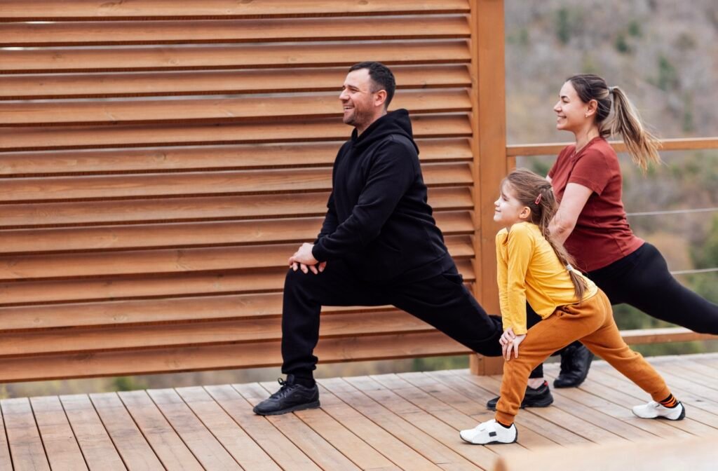 Happy family are stretching outdoors.