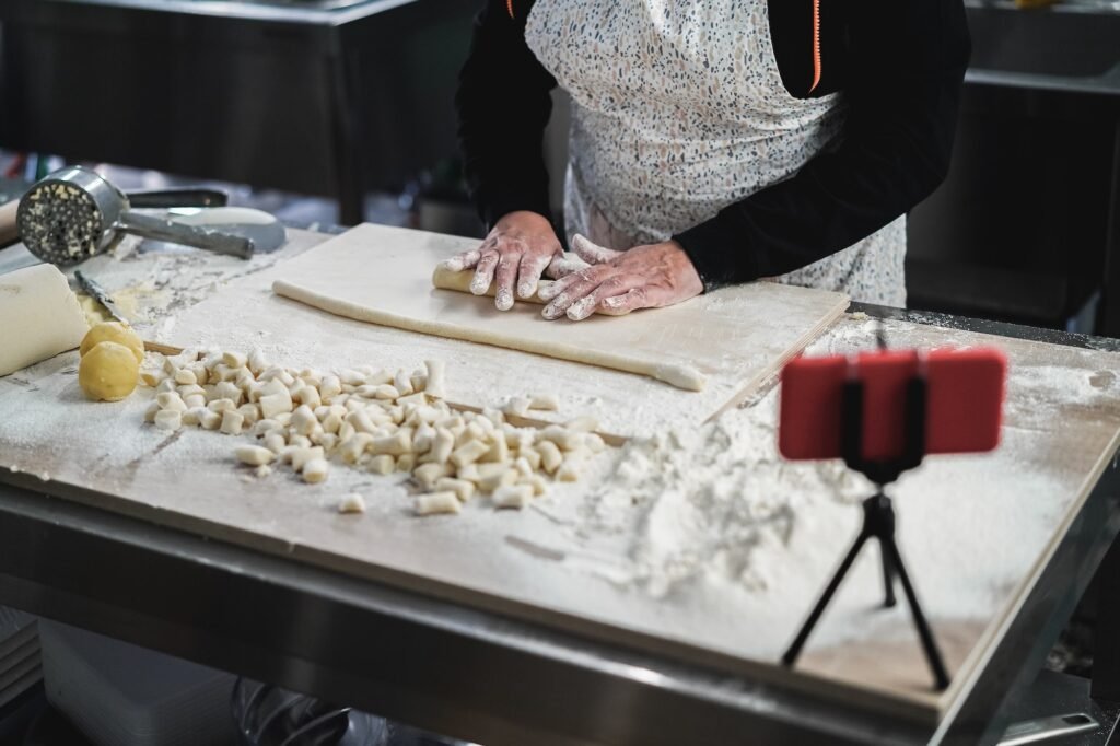Woman streaming online italian cooking lesson of gnocchis with mobile phone