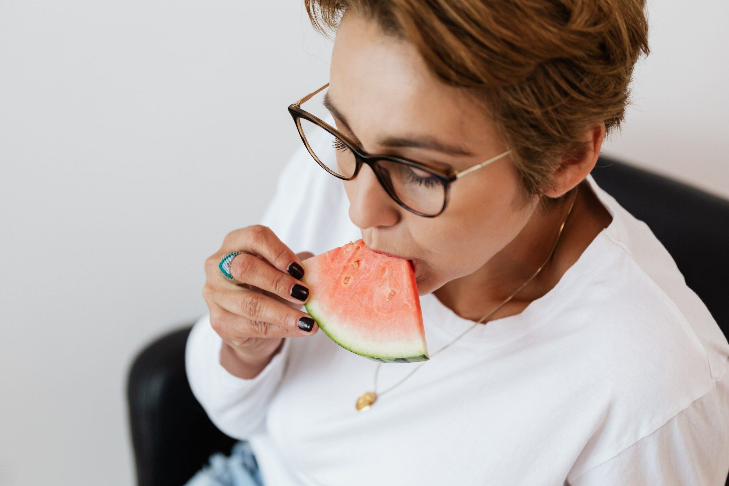 Crop woman enjoying refreshing watermelon at home