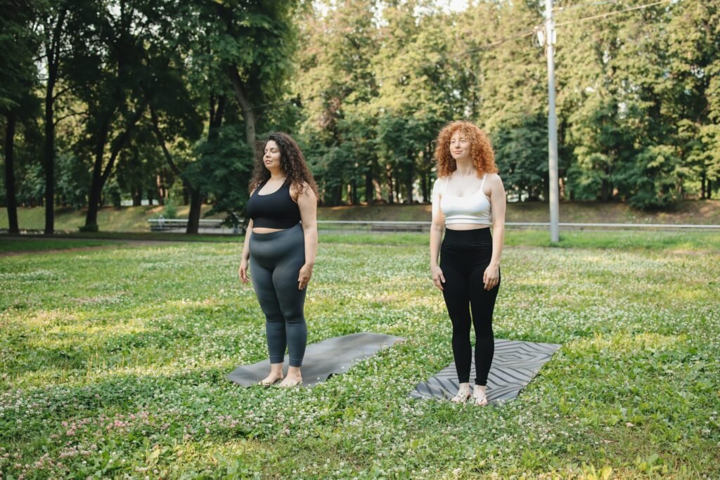 wo Women in Leggings Standing on Yoga Mat in the Park