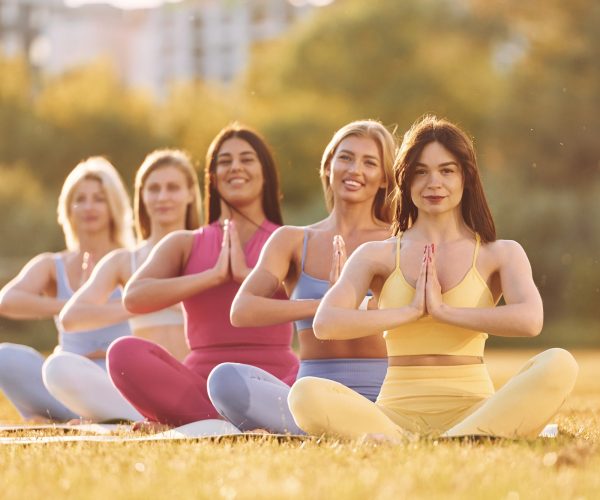 Calm meditation in lotus pose. Group of women have fitness outdoors on the field together