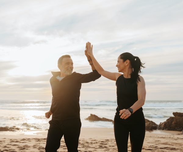 Cheerful mature european couple jogging, give high five, enjoy workout together in morning