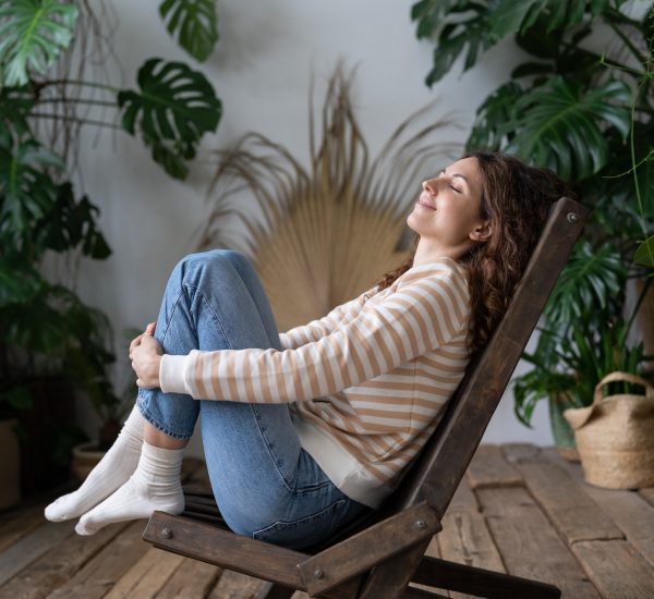 Happy calm peaceful woman dreaming with closed eyes and smile on face in tropical greenhouse