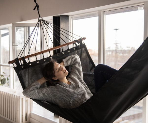 Tired woman sleeping in cozy hammock in flat