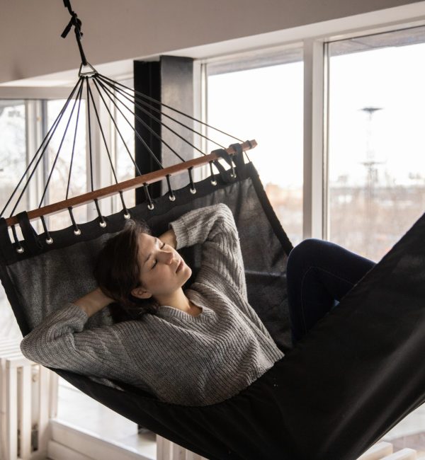 Tired woman sleeping in cozy hammock in flat