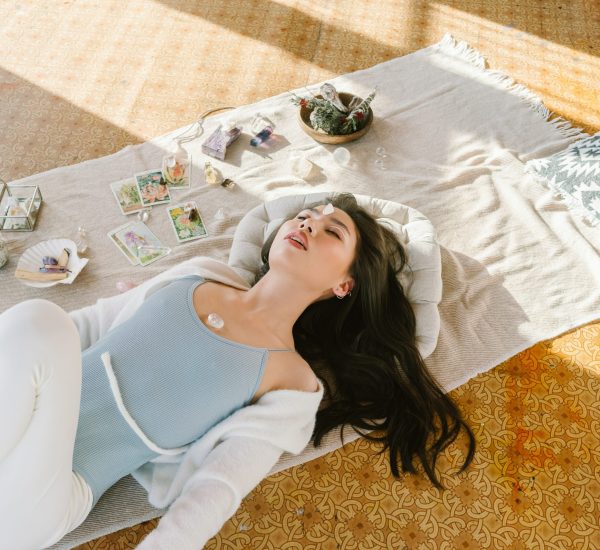 Serene Asian woman lying with chakra stone on chest