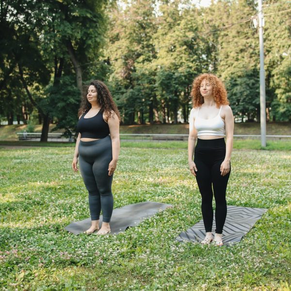 wo Women in Leggings Standing on Yoga Mat in the Park