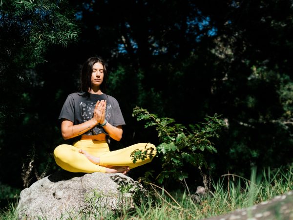 Photo of Woman Doing Yoga While Sitting on Rock