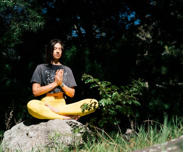 Photo of Woman Doing Yoga While Sitting on Rock