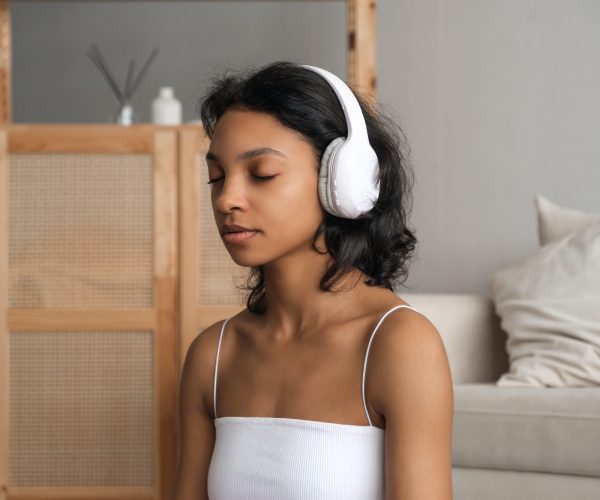 Wellbeing and wellness concept banner with relaxed young woman meditating in headphones