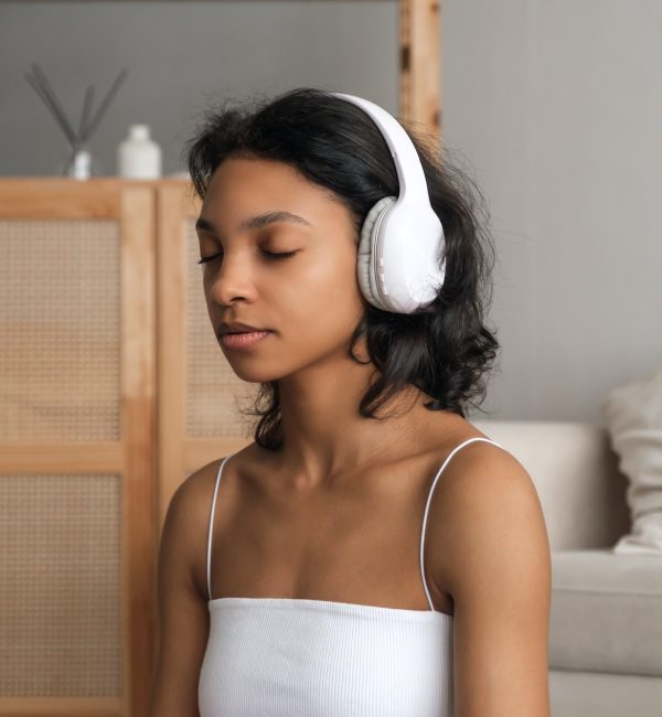 Wellbeing and wellness concept banner with relaxed young woman meditating in headphones